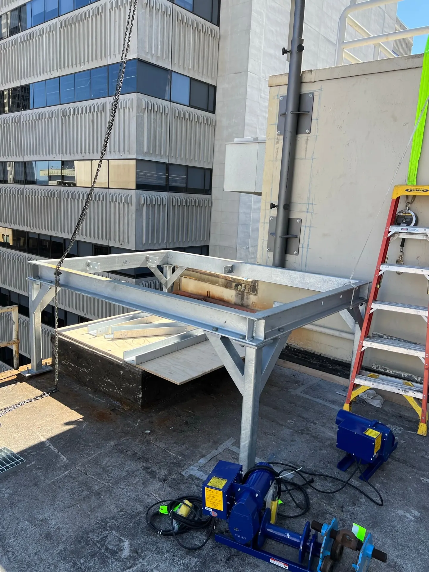 Davit arm assembly and rigging staged on the roof for piece-by-piece lowering.