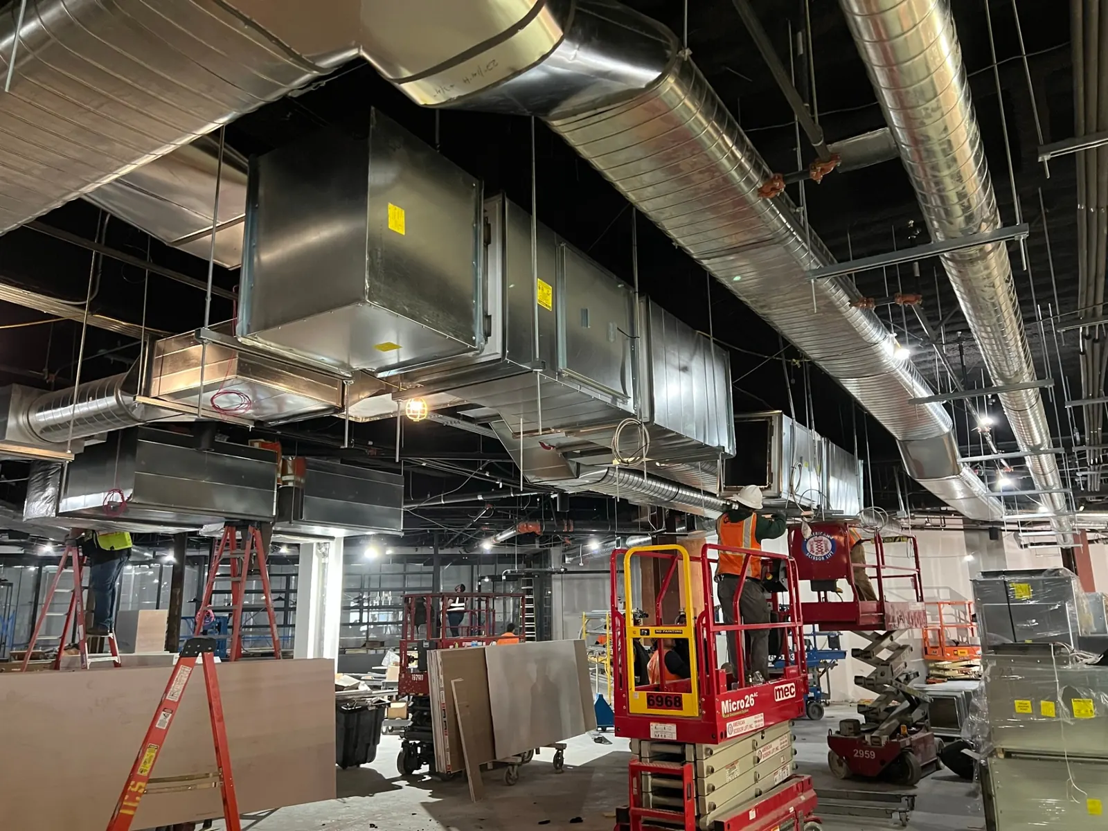 Main grease duct run installed alongside supply and exhaust ductwork above the finished ceiling.